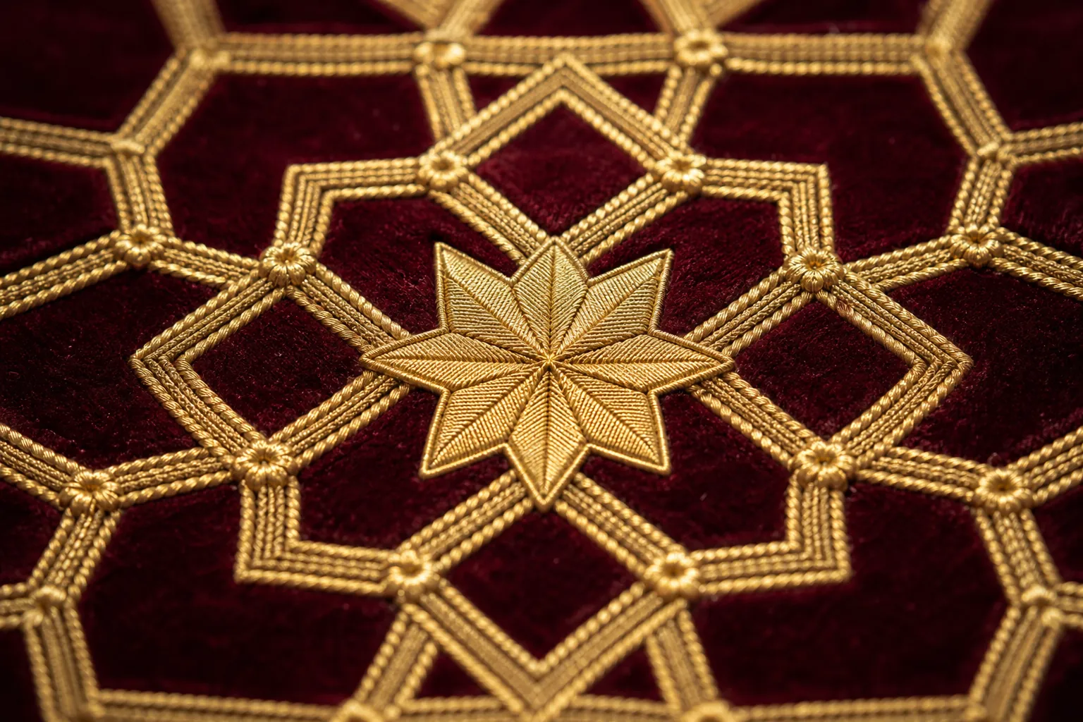 Traditional Arabic eight-point star geometric embroidery in gold on burgundy velvet